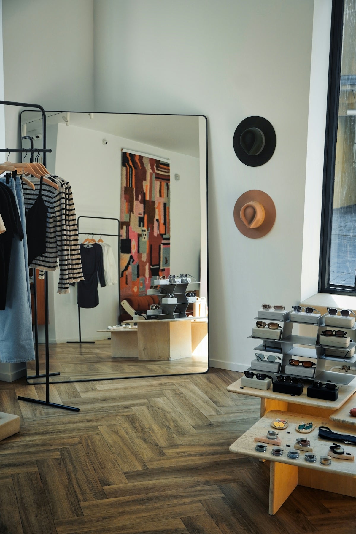 A clothing store with clothes on racks and a mirror