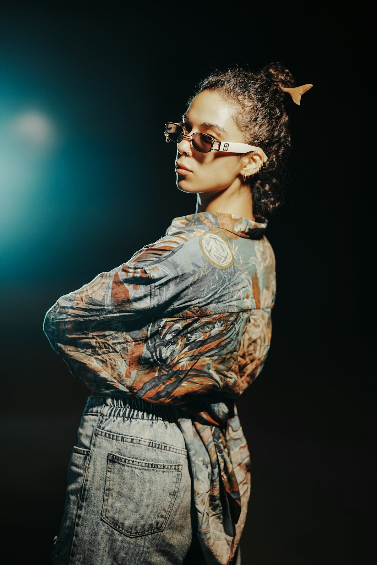 Woman with curly hair wearing sunglasses and patterned shirt