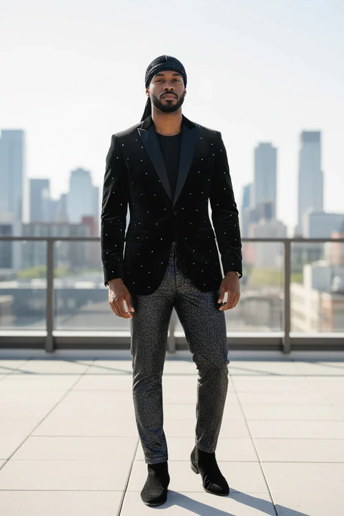 Man in a black blazer with star patterns standing on a rooftop with city skyline in the background