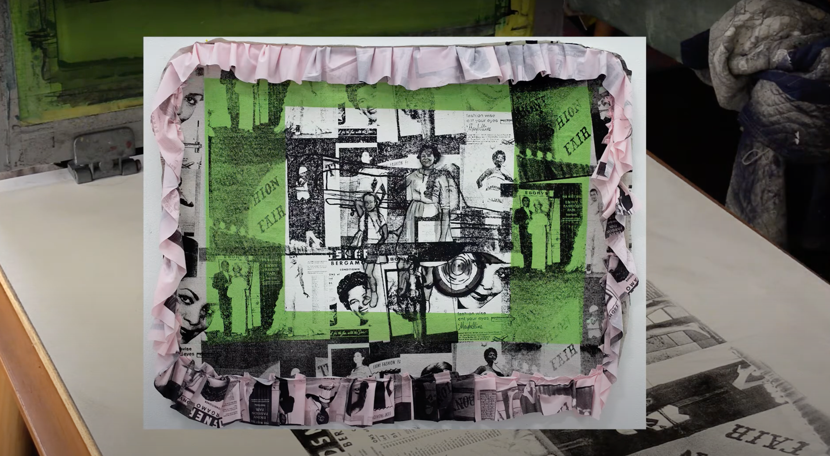 Collage art piece with black and white images on a green background, framed with pink ruffled trim.